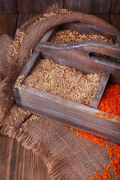 Granos en caja de madera sobre tela de saco sobre fondo de madera — Foto de Stock