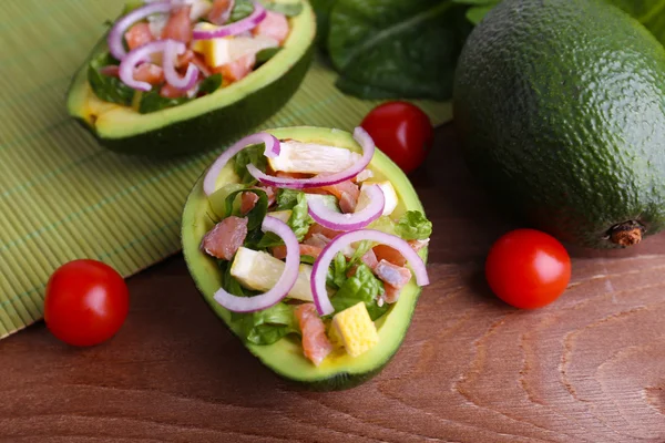 Tasty salad in avocado on table and bamboo napkin close-up — Stock Photo, Image