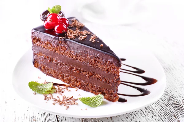 Delicious chocolate cake on plate on table on light background — Stock Photo, Image