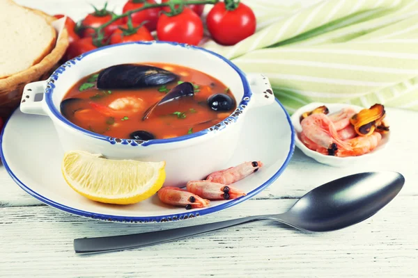 Smakfull suppe med reker, blåskjell, tomater og svarte oliven i bolle på trebakgrunn – stockfoto