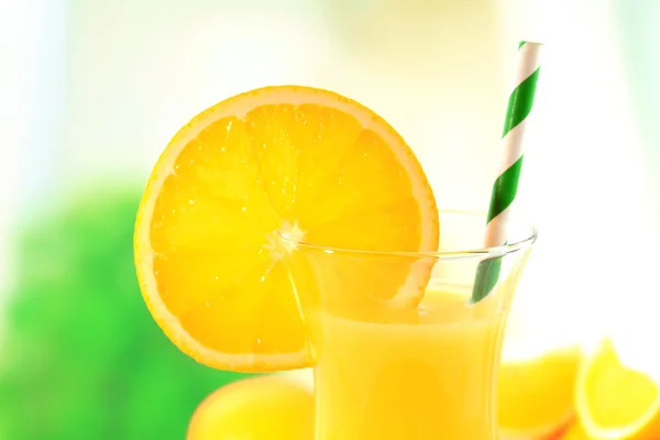 Стекло апельсинового сока с соломой и ломтиками на ярком фоне — стоковое фото