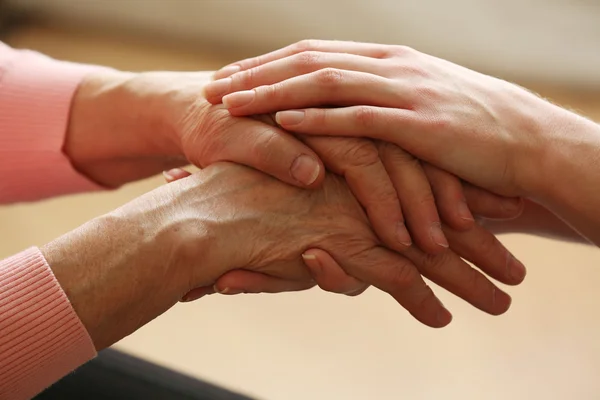 Vecchi e giovani che si tengono per mano su sfondo chiaro, primo piano — Foto Stock