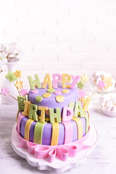 Delicious birthday cake on table on brick wall background — Stock Photo, Image