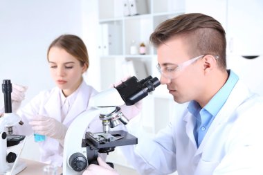 Laboratuar mikroskobu ile genç kadın ve erkek bilim adamları