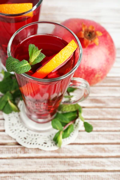 Pomegranate drink in glasses with mint and slices of orange on color wooden planks background — Stock Photo, Image