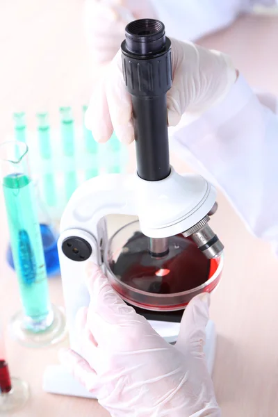 Mãos de cientistas masculinos e femininos usando microscópio em laboratório — Fotografia de Stock