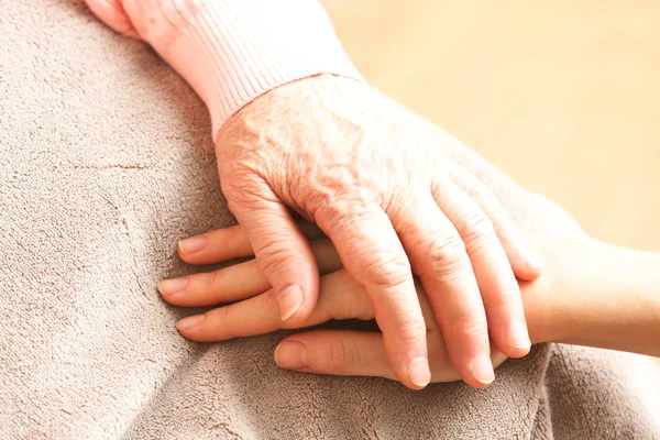 Old and young holding hands on light background, closeup — Stock Photo, Image