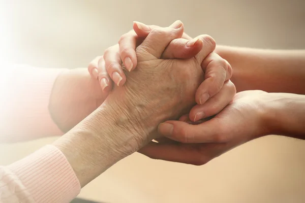 Old and young holding hands on light background, closeup — Stock Photo, Image