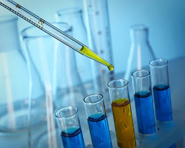 Pipette adding fluid to the one of test-tubes close-up — Stock Photo, Image