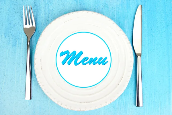Plate with text "Menu", fork and knife on color wooden background — Stock Photo, Image