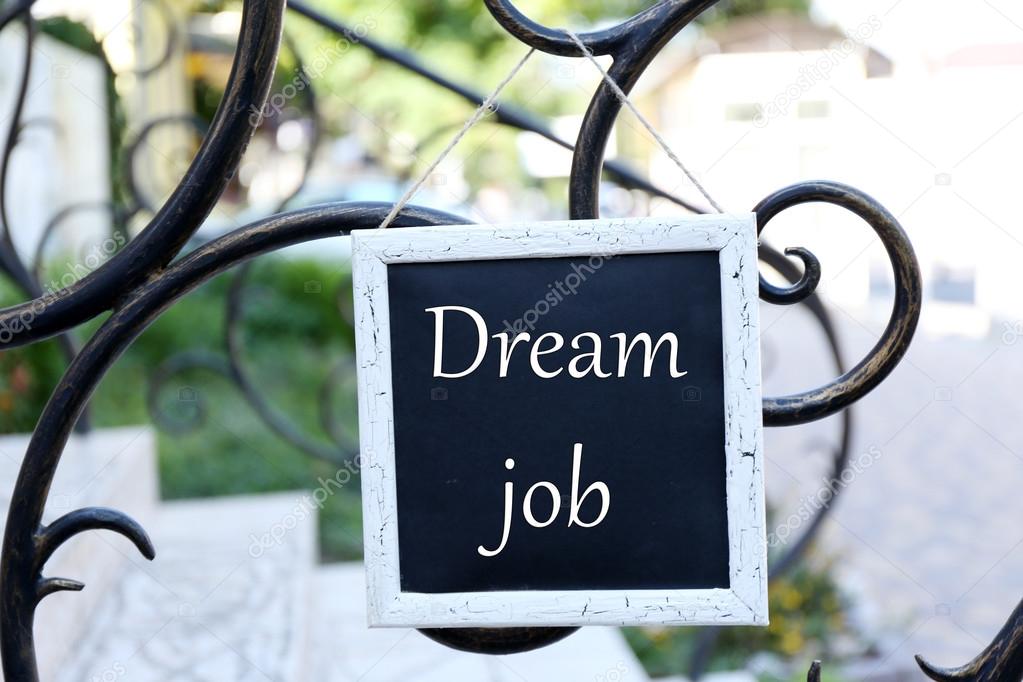 Signboard with Dream Job text on it hanging on metal fence