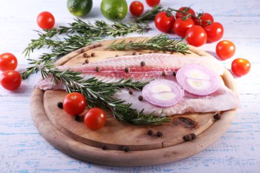 Bitki, baharat ve sebzeler kesme tahtası ve renk ahşap masa arka plan üzerinde Pangasius fileto