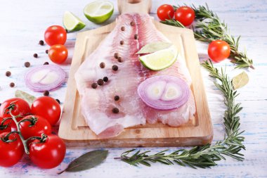 Bitki, baharat ve sebzeler kesme tahtası ve renk ahşap masa arka plan üzerinde Pangasius fileto