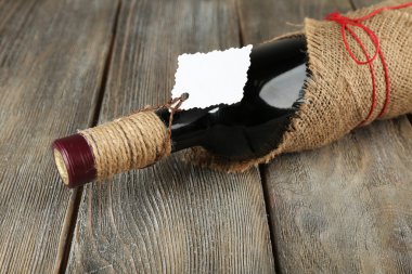 Çuval bezi bez ahşap plakalar arka plan üzerinde kırmızı şarap şişesi sarılı