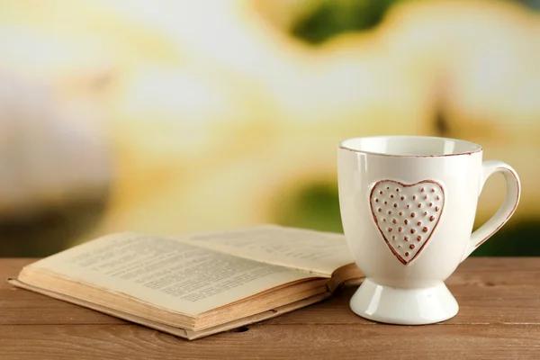 Cup of tea and book on table, on bright background — Stock Photo, Image