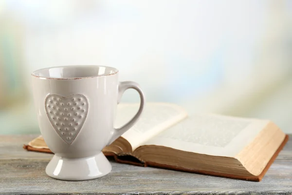 Cup of tea and book on table, on light background — Stock Photo, Image