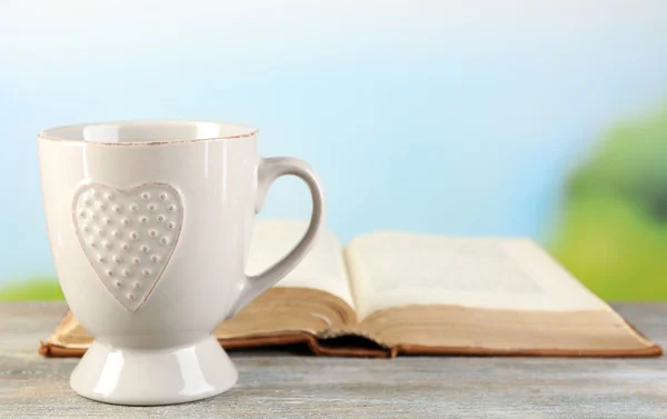 Cup and book on table, on bright background — Stock Photo, Image