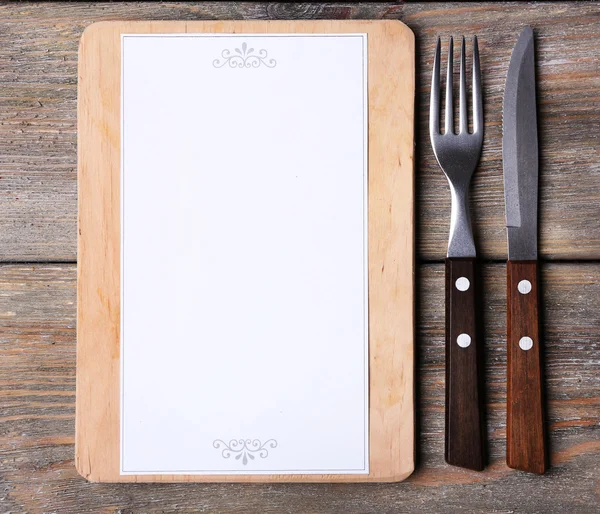 Placa de corte com folha de menu de papel em tábuas de madeira rústica fundo — Fotografia de Stock
