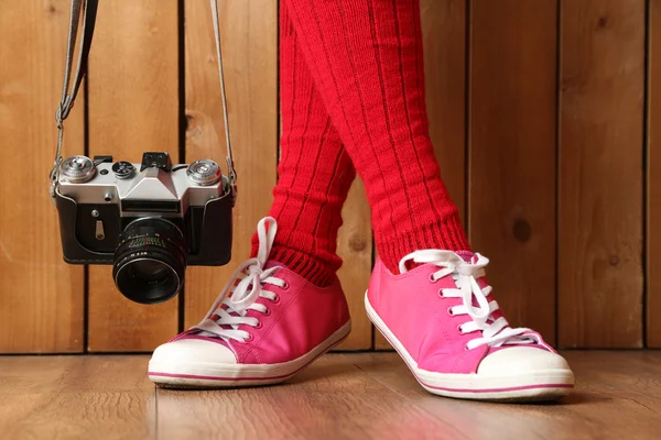 Girl in sneakers with retro photo camera in room — Stock Photo, Image