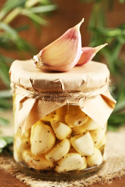 Canned garlic in glass jar on wooden background — Stock Photo, Image