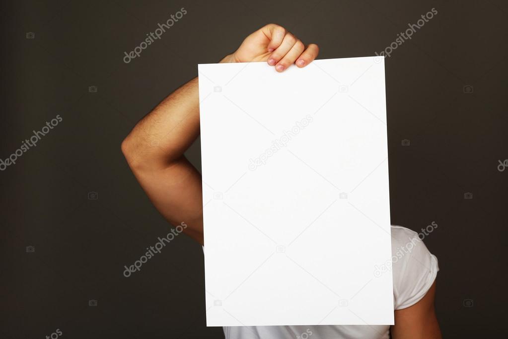 Blank sheet of paper in male hand on dark background