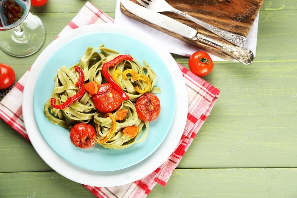 Pasta salad with pepper, carrot and tomatoes on wooden table background