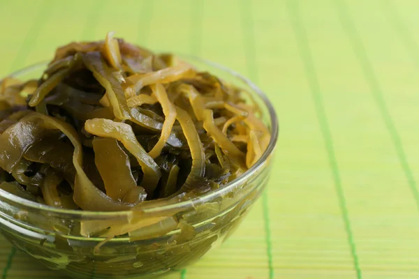 Seaweed in glass bowl on bamboo mat background — Stock Photo, Image