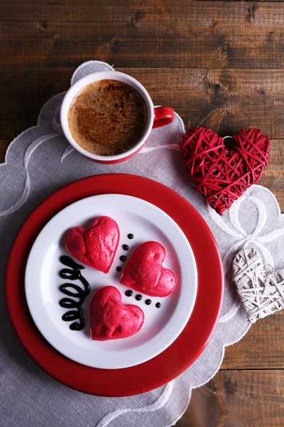 Cookies in form of heart in plate with cup of coffee on napkin, on rustic wooden planks background — Stock Photo, Image