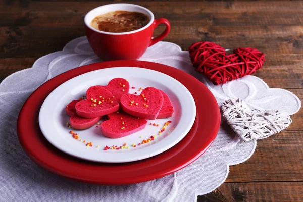 Biscuits en forme de coeur dans une assiette avec une tasse de café sur une serviette, sur des planches de bois rustiques fond — Photo