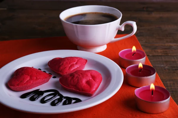 Печенье в форме сердца в тарелке с чашкой кофе и свечами на салфетке, на деревенском деревянном фоне — стоковое фото