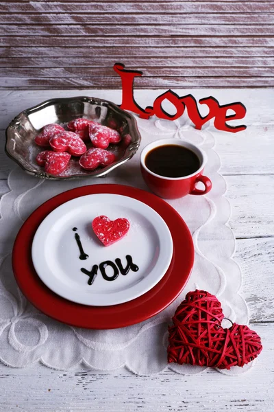 Печенье в форме сердца на тарелке с надписью "Я люблю тебя" на фоне цветного деревянного стола — стоковое фото