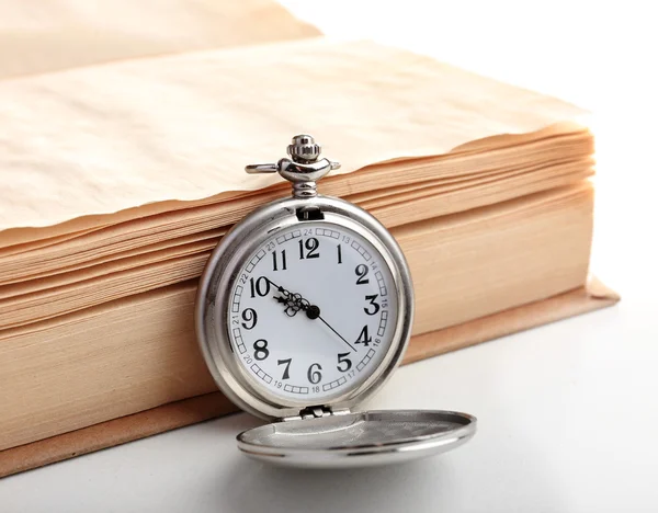 Silver pocket clock and book on white table — Stock Photo, Image