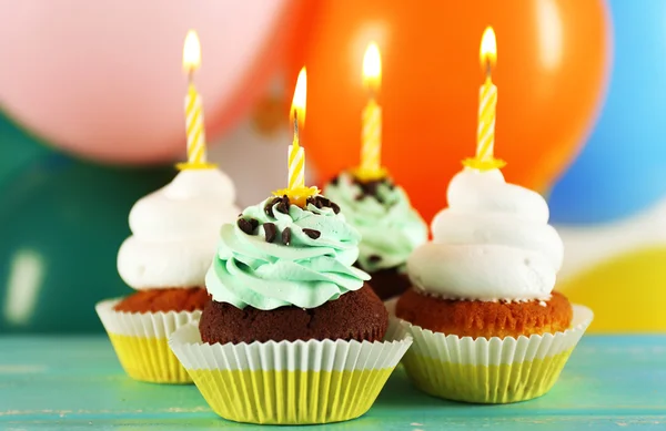 Deliciosos cupcakes de aniversário na mesa em fundo brilhante — Fotografia de Stock