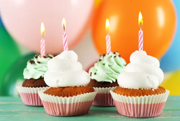 Deliciosos cupcakes de aniversário na mesa em fundo brilhante — Fotografia de Stock