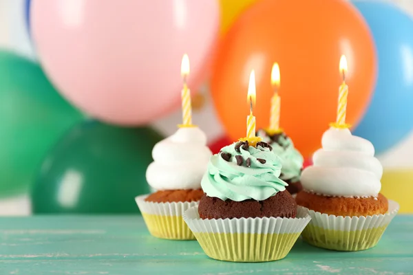 Deliciosos cupcakes de aniversário na mesa em fundo brilhante — Fotografia de Stock