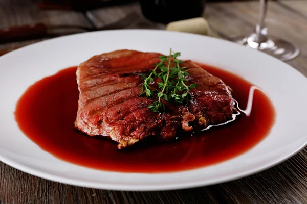 Grilled steak in wine sauce on plate on table close up — Stock Photo, Image