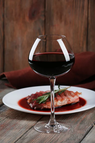 Bife grelhado em molho de vinho com copo de vinho em fundo de madeira — Fotografia de Stock