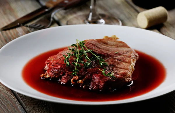 Grilled steak in wine sauce on plate on table close up — Stock Photo, Image