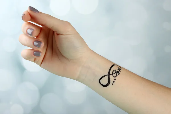 Vrouwelijke arm met tattoo — Stockfoto