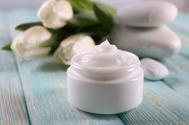 Çiçek ve spa taşlar ahşap arka plan üzerinde kozmetik krem