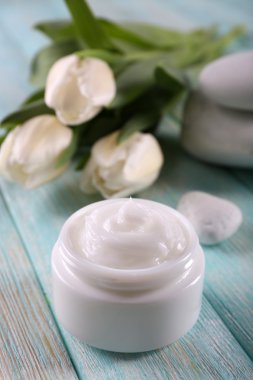 Çiçek ve spa taşlar ahşap arka plan üzerinde kozmetik krem