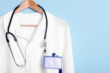 Doktor stetoskop askı üzerinde mavi arka plan üzerinde paltoyla