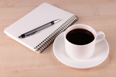 Fincan kahve üzerinde uçan daire ile defter ve kalem ahşap masa arka plan üzerinde