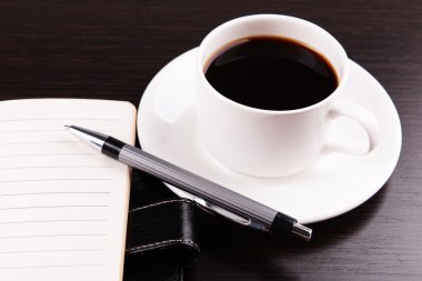 Fincan kahve tabağı ile günlüğü üzerinde ve ahşap masa arka plan üzerinde kalem