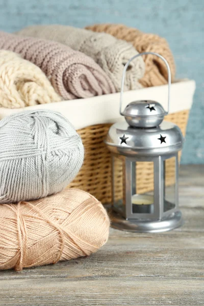 Pletení oblečení a příze v koši, na dřevěné pozadí — Stock fotografie