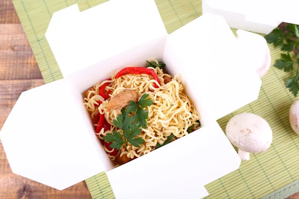Chinese noodles in takeaway box on mat background — Stock Photo, Image
