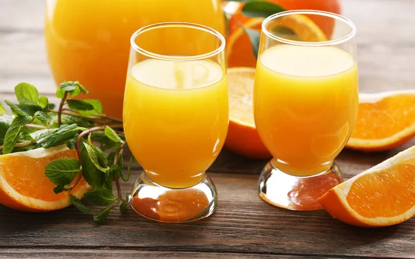 Copo de suco de laranja e fatias em fundo de mesa de madeira — Fotografia de Stock