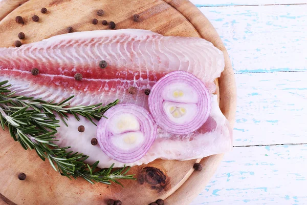 Filetto di pangasio con erbe e spezie sul tagliere e sullo sfondo del tavolo in legno a colori — Foto Stock