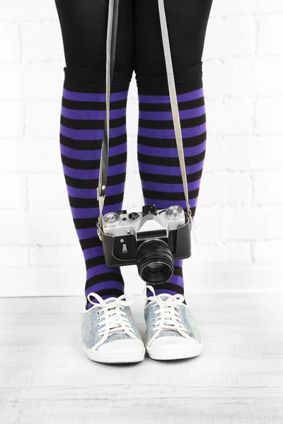 Girl in sneakers with retro photo camera in room — Stock Photo, Image