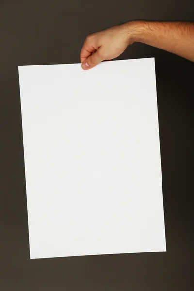 Blank sheet of paper in male hand on dark background — Stock Photo, Image